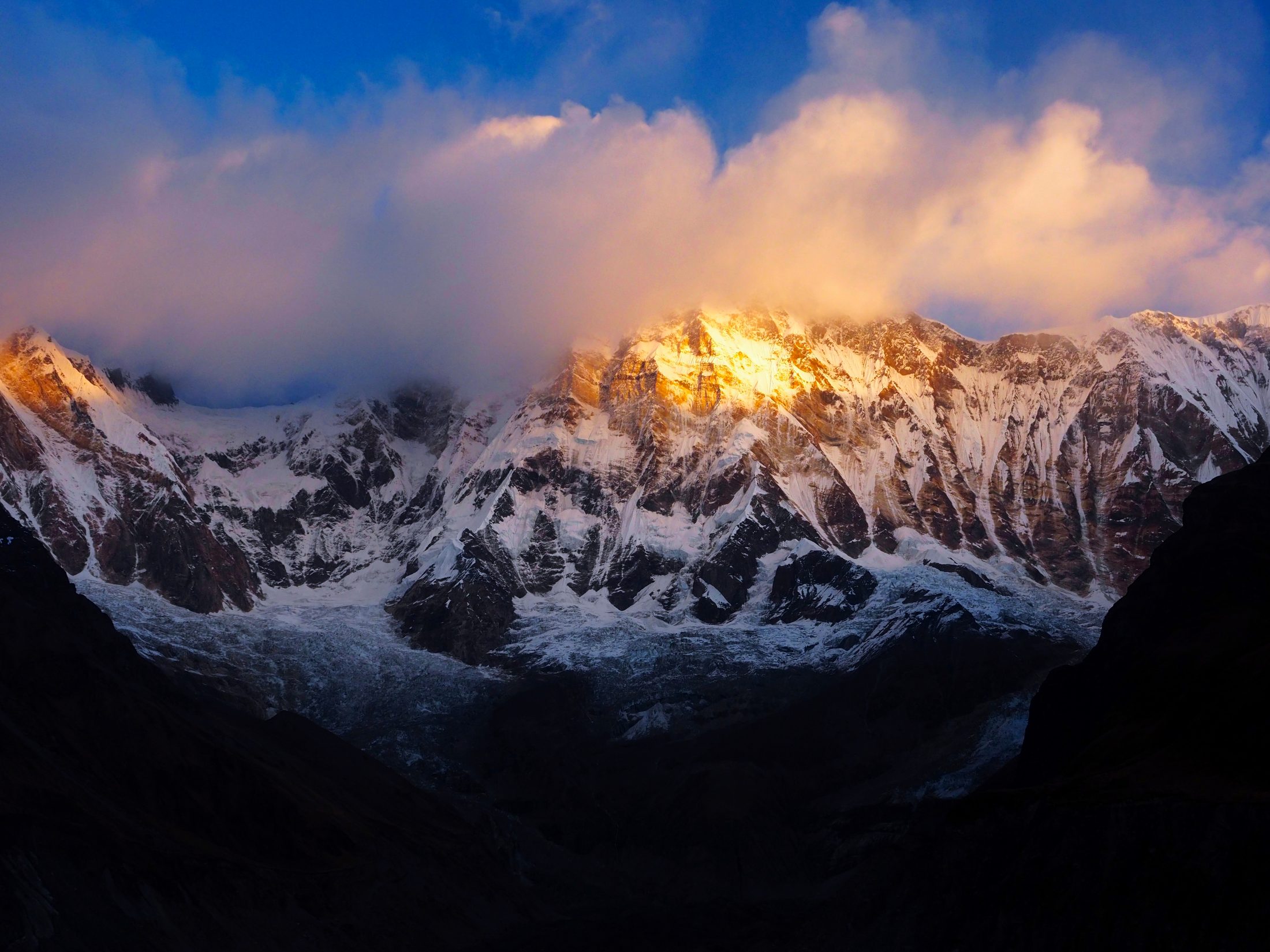 Alpenglow on the Annapurna range at dawn, cloud breaking over the summit ridge